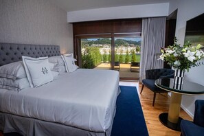A bedroom with a large bed, a view of the outdoors, a small table, and a chair. - Solar do Requeijo by Luna Hotels & Resorts (Giela)
