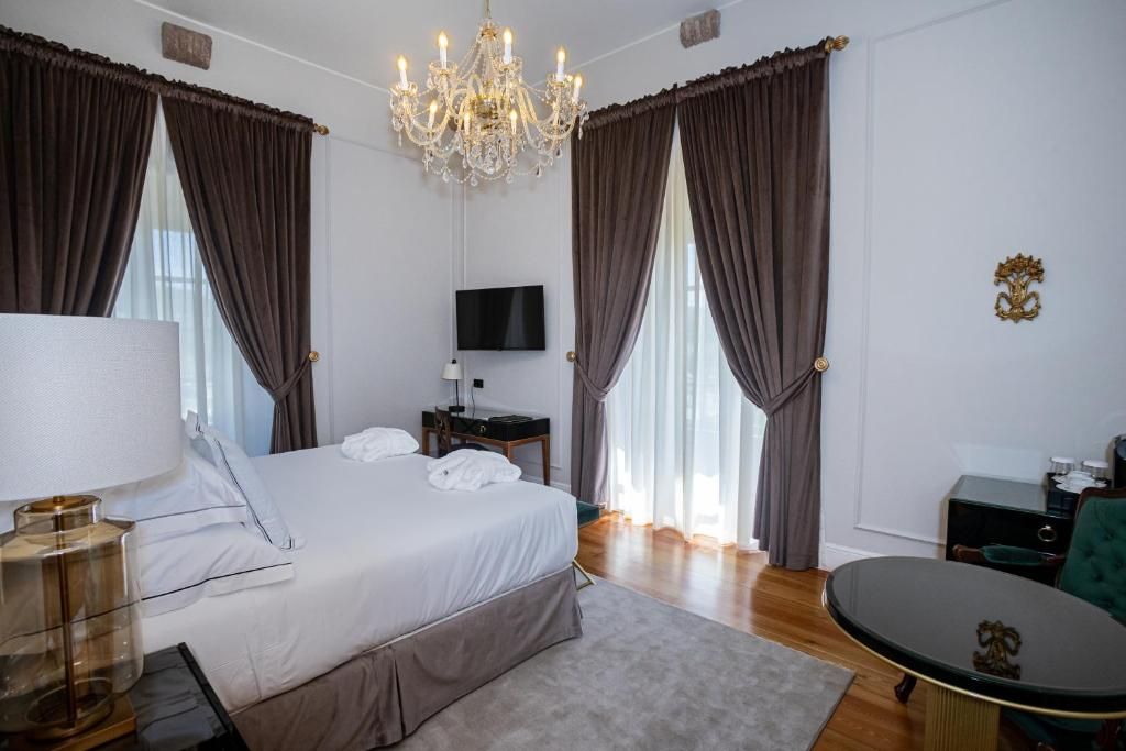 A hotel room with a bed, a TV, a desk, and a chandelier.