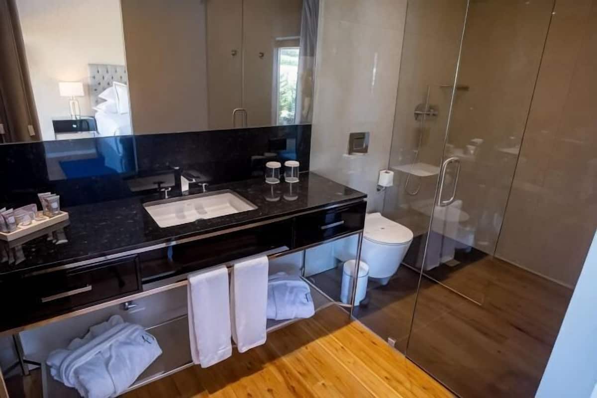 Casa de banho moderna com bancada preta, lavatório, sanita e zona de duche.