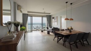 A modern hotel room with a dining area, a large window with a view, and a balcony. - Diamond Island Highfloor RiverView 8min to D1 (Ho Chi Minh City)