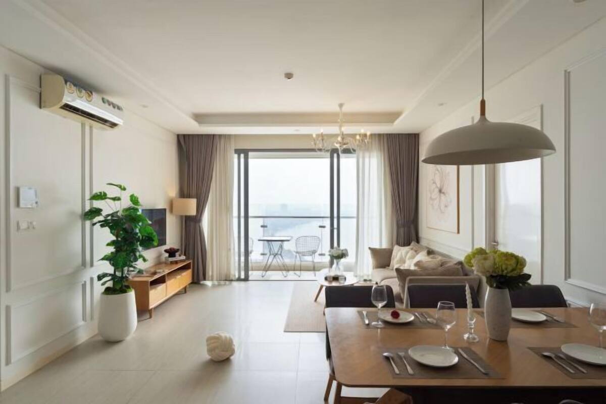A modern hotel room with a dining area, a balcony with a view, and a large window.