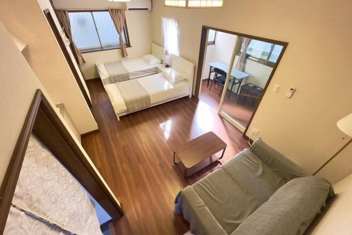 Ein kleines Zimmer mit Bett, Schlafsofa, Tisch und Spiegel.