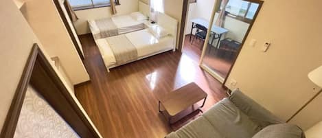 A compact room with a bed, a sofa, a small table, and a mirror.