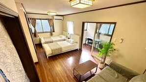 A compact hotel room with a bed, a sofa, a small table, and a potted plant. - Shinjuku 11 mins Private kitchen and bathroom Up to 4 guests Newly renovated Garden villa (Tokyo)
