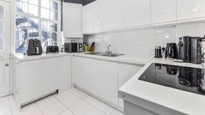 A modern kitchen with white cabinets, a built-in oven, and a window providing natural light. - Stylish 3-Bedroom Flat in Belsize Park – Perfect for Families & Business Trips! (London)