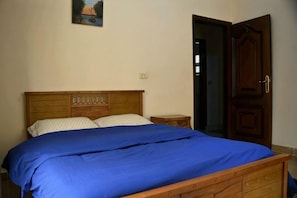 A bedroom with a wooden bed, a nightstand, and a door. - Rino Residential Apartment (New Cairo City)