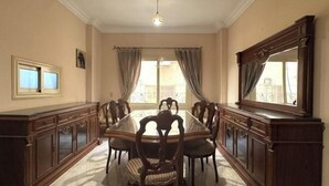 Uma sala de jantar com uma mesa comprida, cadeiras, um armário e um espelho grande.