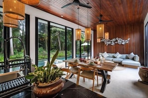 A modern interior with a dining area, seating, and large windows. - Villa Surya by BaliSuperHost (Bali)