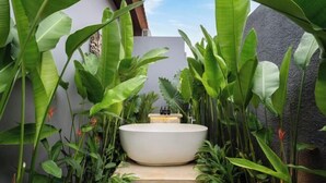 A spa area with a large white bathtub surrounded by lush green plants. - Villa Surya by BaliSuperHost (Bali)