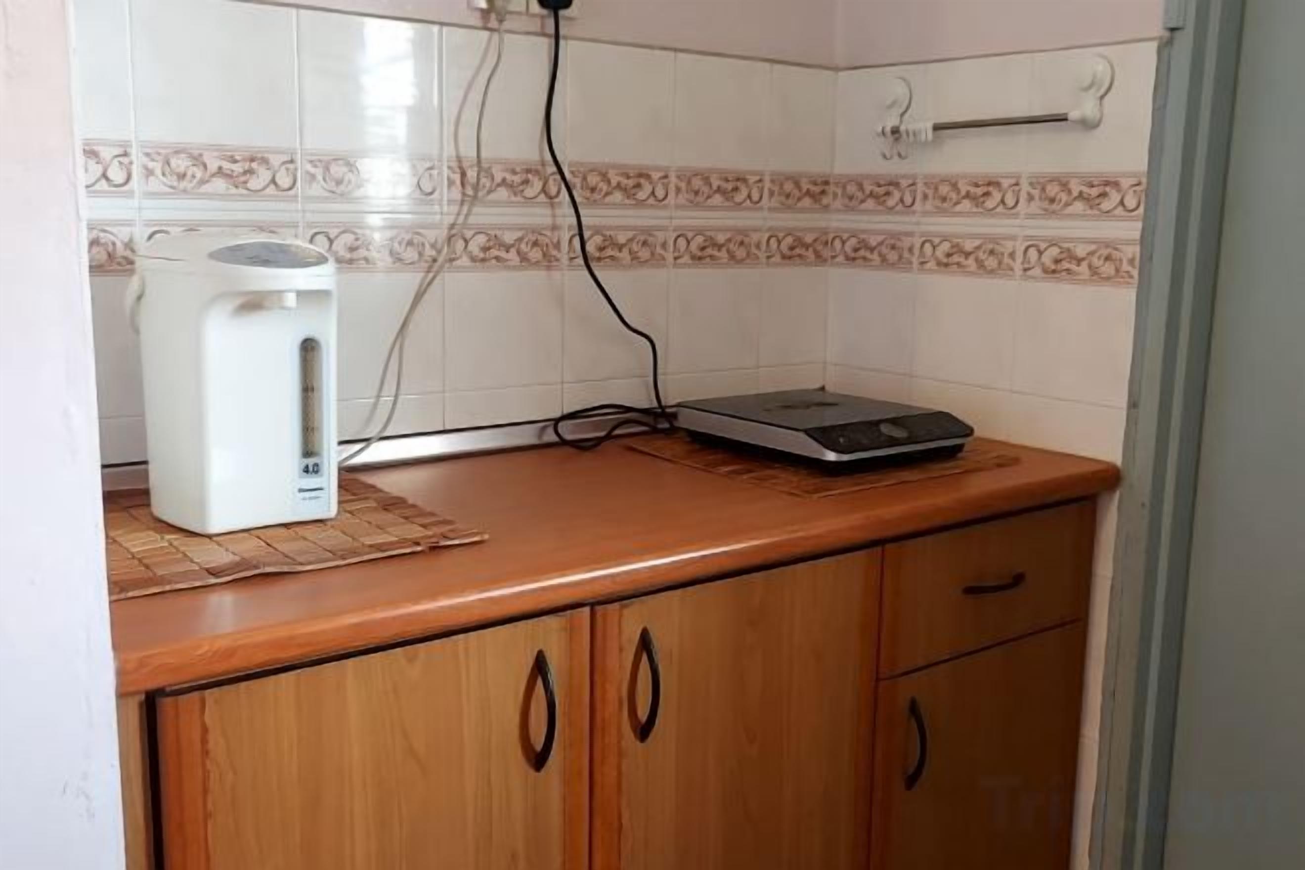 A kitchen with a coffee maker, a scale, and a tiled backsplash.