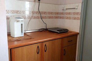 A kitchen with a coffee maker, a scale, and a tiled backsplash. - Glory 2 Beds Room by Alpine (Port Dickson)