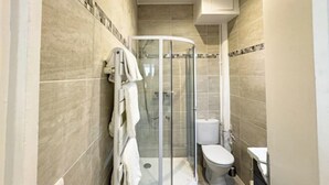 Un baño con ducha de vidrio, inodoro y lavamanos.