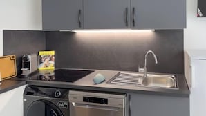 Una cocina compacta equipada con lavavajillas, un lavaplatos y una cafetera.