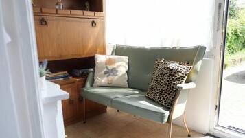 A room with a green sofa, a leopard print pillow, and a wooden cabinet.