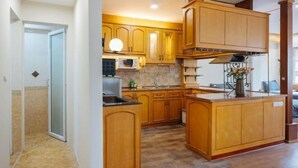 A modern kitchen with wooden cabinets, a central island, and a microwave. - VietHOME - 22 Pho Hue - Apartment 401 (Hanoi)