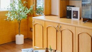 A wooden cabinet with a shelf, a potted plant, and a book titled 'NEW YORK' on top. - VietHOME - 22 Pho Hue - Apartment 401 (Hanoi)