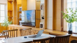 A modern hotel room with a large flat-screen TV, wooden furniture, and a potted plant. - VietHOME - 22 Pho Hue - Apartment 401 (Hanoi)