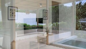A modern indoor space with a glass partition, a seating area with cushions, a small table, and a water feature. - Tropical Peaceful Poolside Retreat by Sea N' Rent (Koh Phangan)