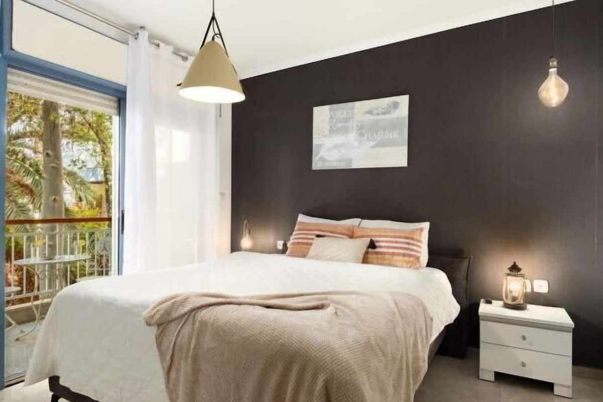 A bedroom with a bed, bedside table, and a window with a view.