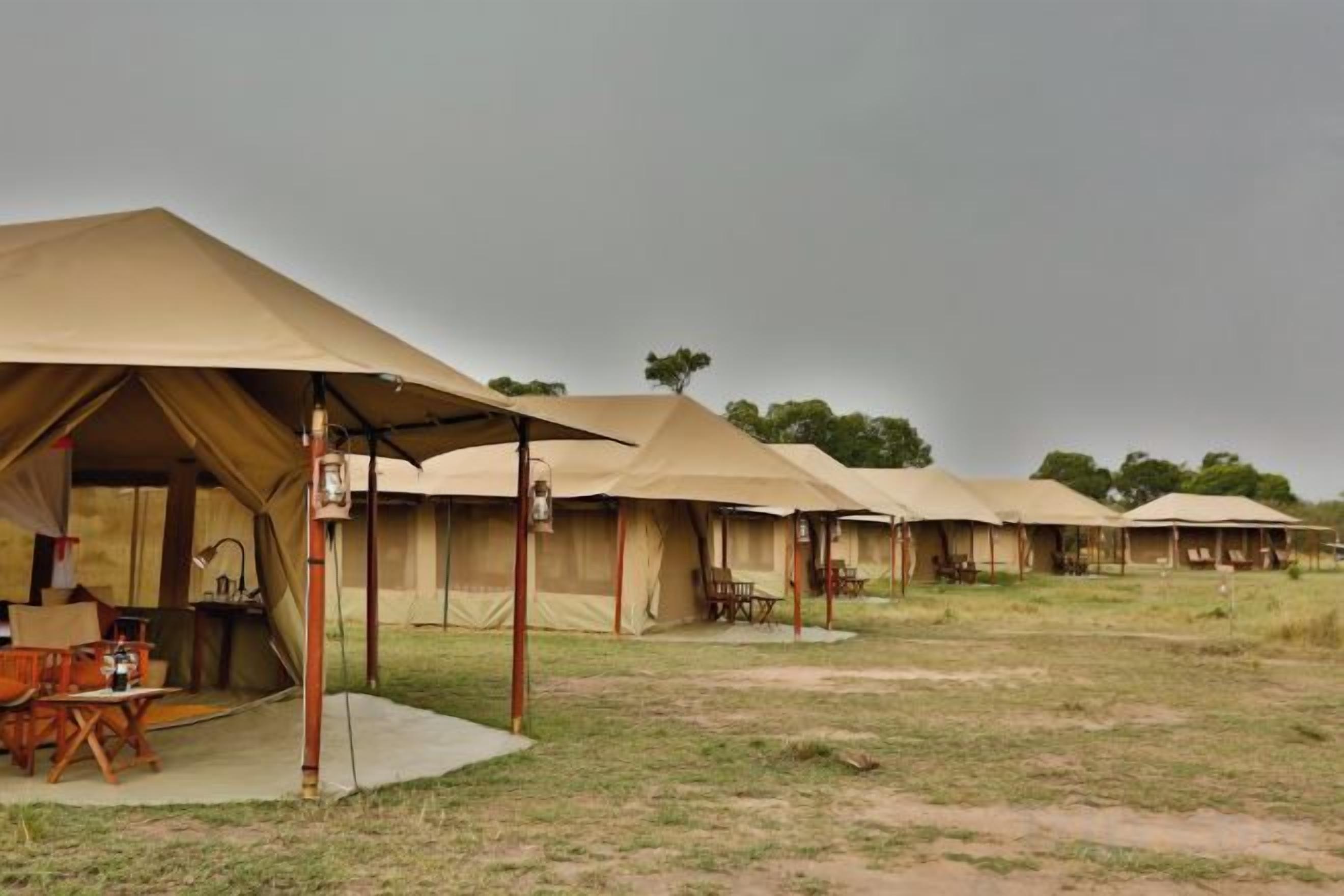 A row of safari tents with a dining area and tables visible in the foreground.