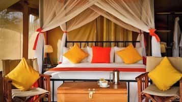 A bed with a canopy, two chairs, a bedside table, and a lamp.