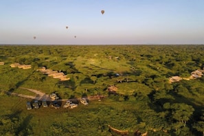 A rural landscape with scattered buildings and hot air balloons in the distance.