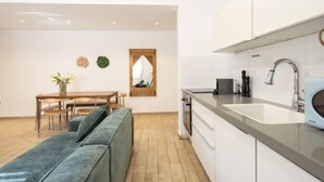Une cuisine moderne équipée d’un four encastré, d’un évier et d’un four à micro-ondes. Un coin repas avec une table et des chaises est également disponible.