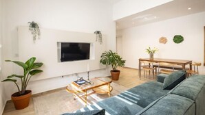 Un salon moderne doté d’un téléviseur à écran plat, d’un canapé, d’une table basse et d’un coin repas avec une table et des chaises.
