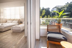 Ein Balkon mit Holzstuhl, einem Blumentopf und Blick auf Gebäude und Bäume.