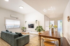 Ein modernes Wohnzimmer mit einer Eckcouch, einem Holzesstisch und einem flachbildfernseher an der Wand.