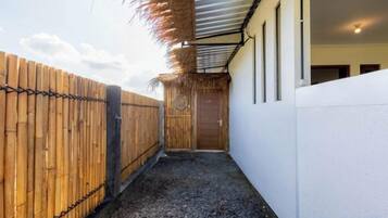 Un pasillo estrecho con una valla de madera a un lado y una pared blanca al otro, que conduce a una puerta.