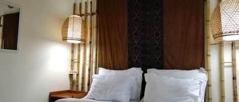 Una habitación de hotel con una cama, dos mesitas de noche, un espejo y dos lámparas fijadas a la pared.