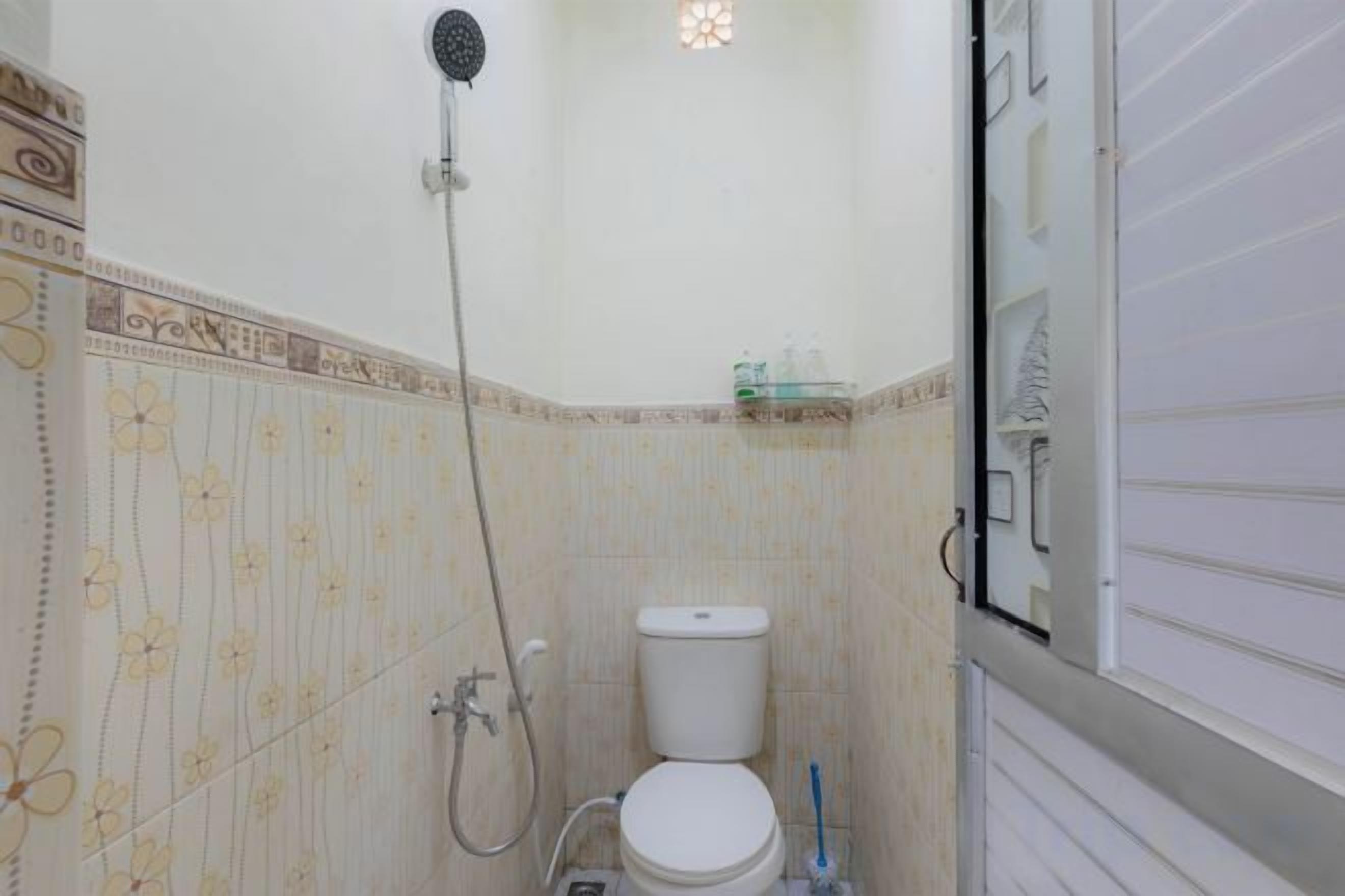 A bathroom with a toilet, shower, and a tiled wall with a floral pattern.