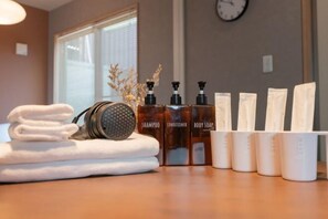 A bathroom with a towel stack, headphones, shampoo, conditioner, body scrub, and shower caddy. - New open！F Maison Kishinosato｜Next to Tenga Chaya Park (Osaka)