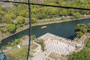 Une rivière où l’on peut naviguer, bordée de verdure et entourée d’une zone délimitée par une clôture, avec des marches descendant vers un bâtiment.