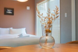 A clear view of a room with a bed, a vase with dried flowers on a table, and a window with blinds. - New open！F Maison Kishinosato｜Next to Tenga Chaya Park (Osaka)