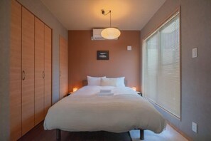 A bedroom with a bed, bedside lamps, a wardrobe, and a window with blinds. - New open！F Maison Kishinosato｜Next to Tenga Chaya Park (Osaka)