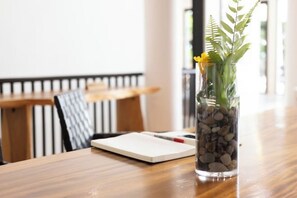 Une table en bois sur laquelle est posé un vase en verre transparent contenant une plante et des fleurs jaunes.