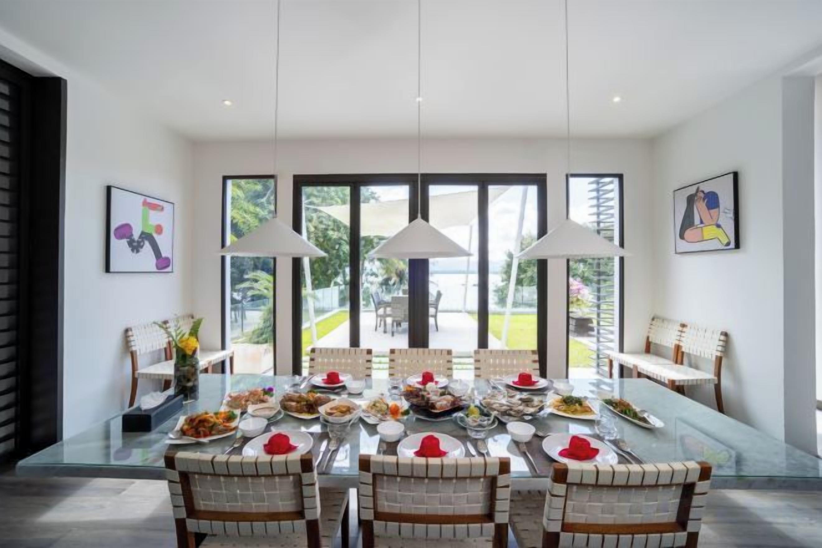 A dining area with a glass table, chairs, and pendant lights.