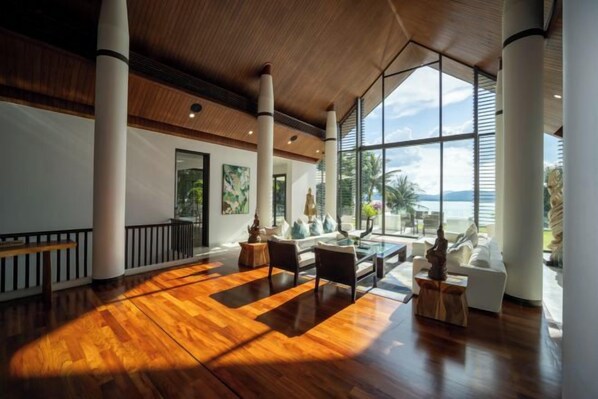 A spacious lobby with a wooden floor, large windows, and a seating area with a view of the outdoors.