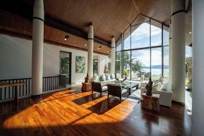 Un vestíbulo amplio con piso de madera, ventanas grandes y una zona de estar con vistas al exterior.