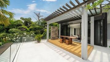 A modern outdoor patio with a wooden deck, a seating area, and a pergola structure.