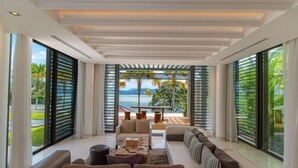 A modern living room with a sofa, coffee table, and a view of the ocean. - Luxury Beachfront Villas & Resort (Phuket)