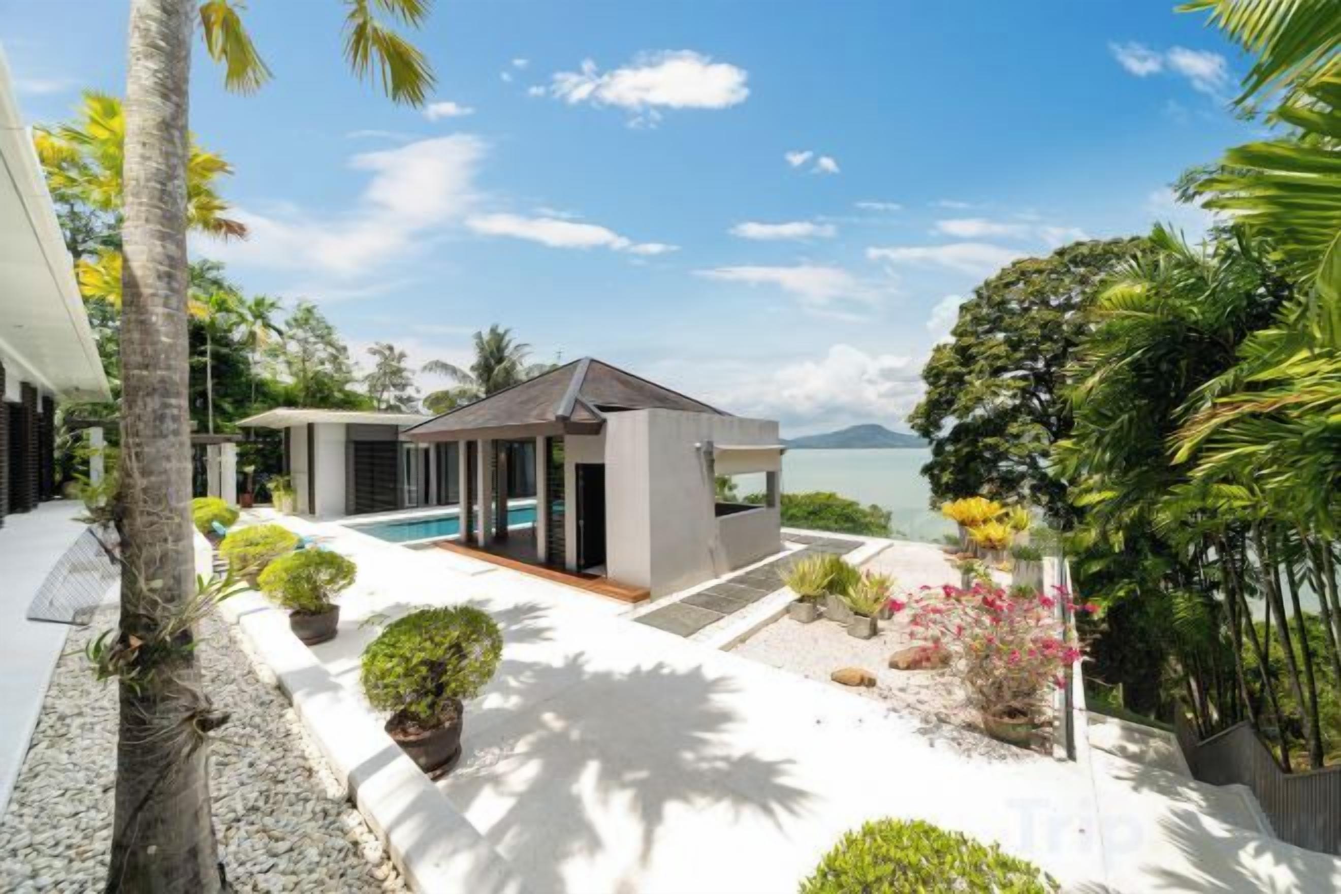 A modern resort with a pool, a covered seating area, and lush tropical landscaping.