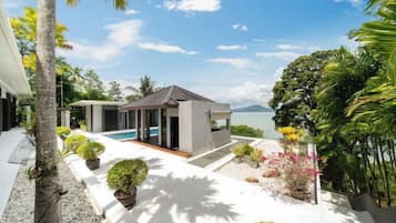 A modern resort with a pool, a covered seating area, and lush tropical landscaping.