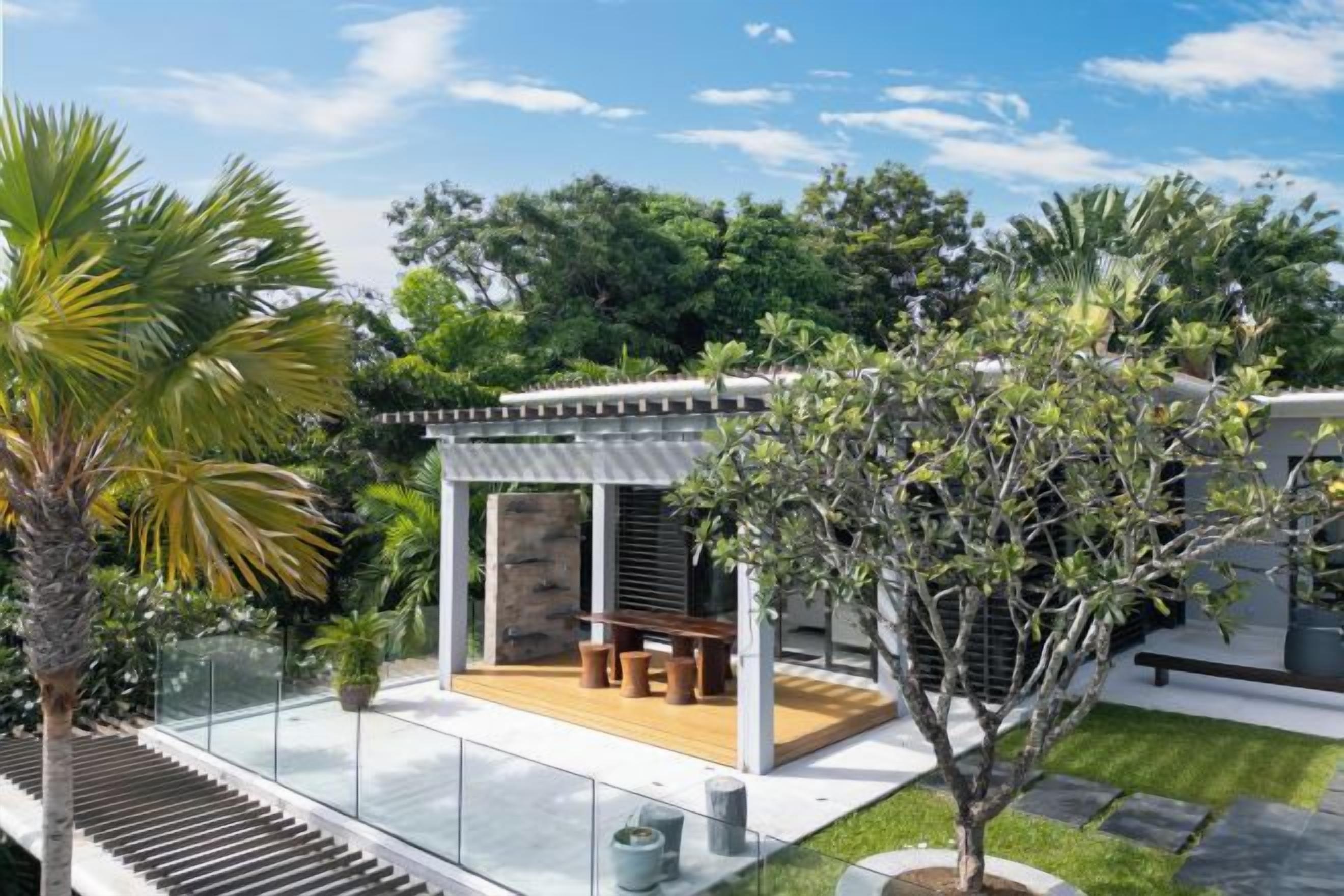 A modern outdoor patio with a wooden deck, seating, and a glass railing.