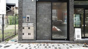 A modern building entrance with a glass door, a metal gate, and a signboard. - KAIGAN HAJIME HUB (Tokyo)