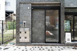 A building entrance with a glass door, a metal elevator, and a QR code sign. - KAIGAN HAJIME HUB (Tokyo)