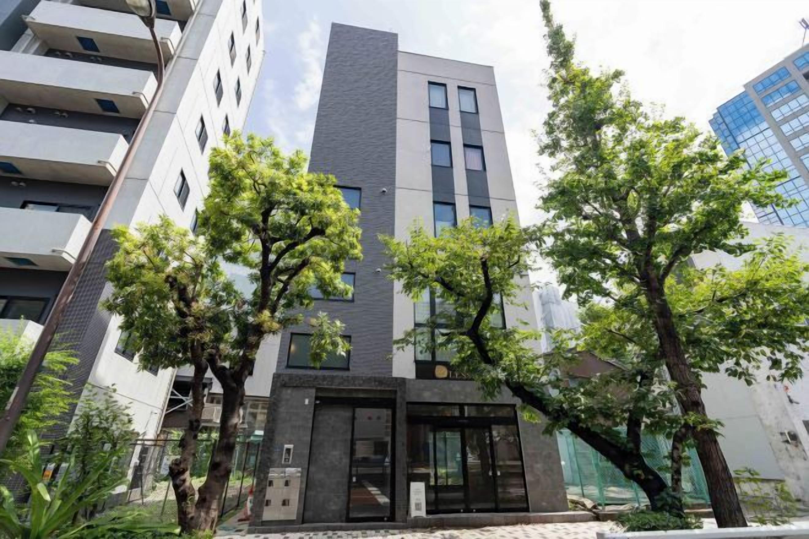 A modern building with a central entrance, surrounded by trees.