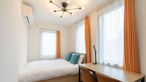 A hotel room with a bed, a desk, and two windows with curtains. - KAIGAN HAJIME HUB (Tokyo)